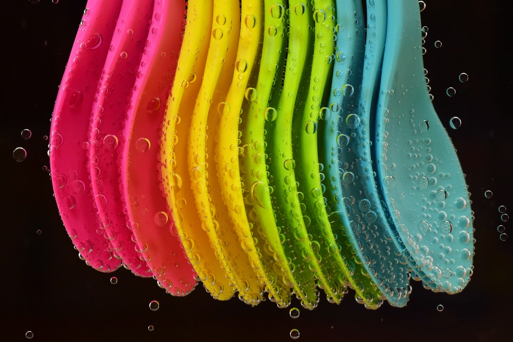 Colourful spoons in water as stock photography